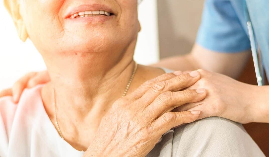 elderly women in pink shirt holding the hand of a caregiver